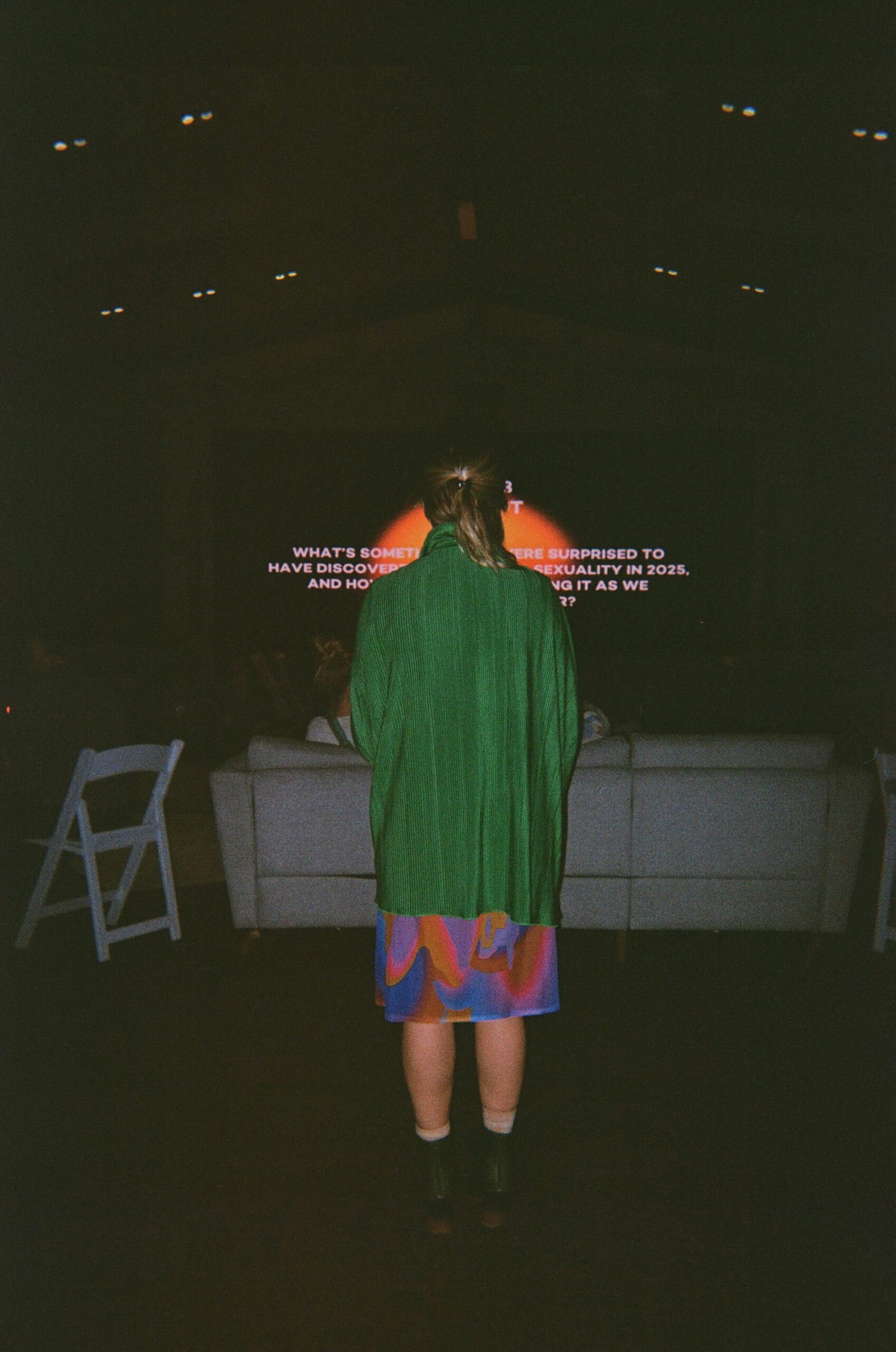 Allie, the founder of the feels, facing away reading off a prompt to facilitate conversation during a feels event