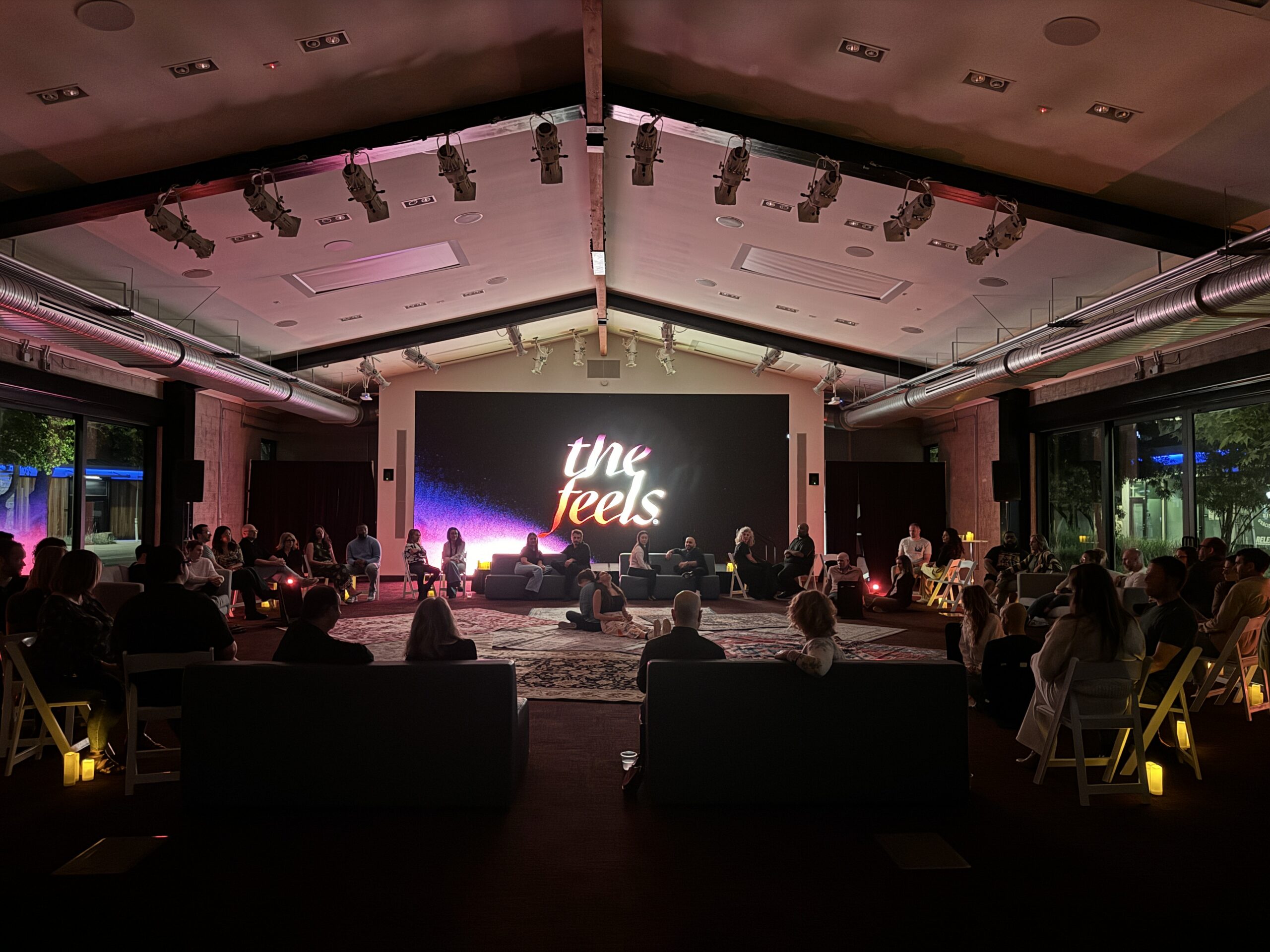 a wide room shot of a feels event where people can be seen sitting on the floor