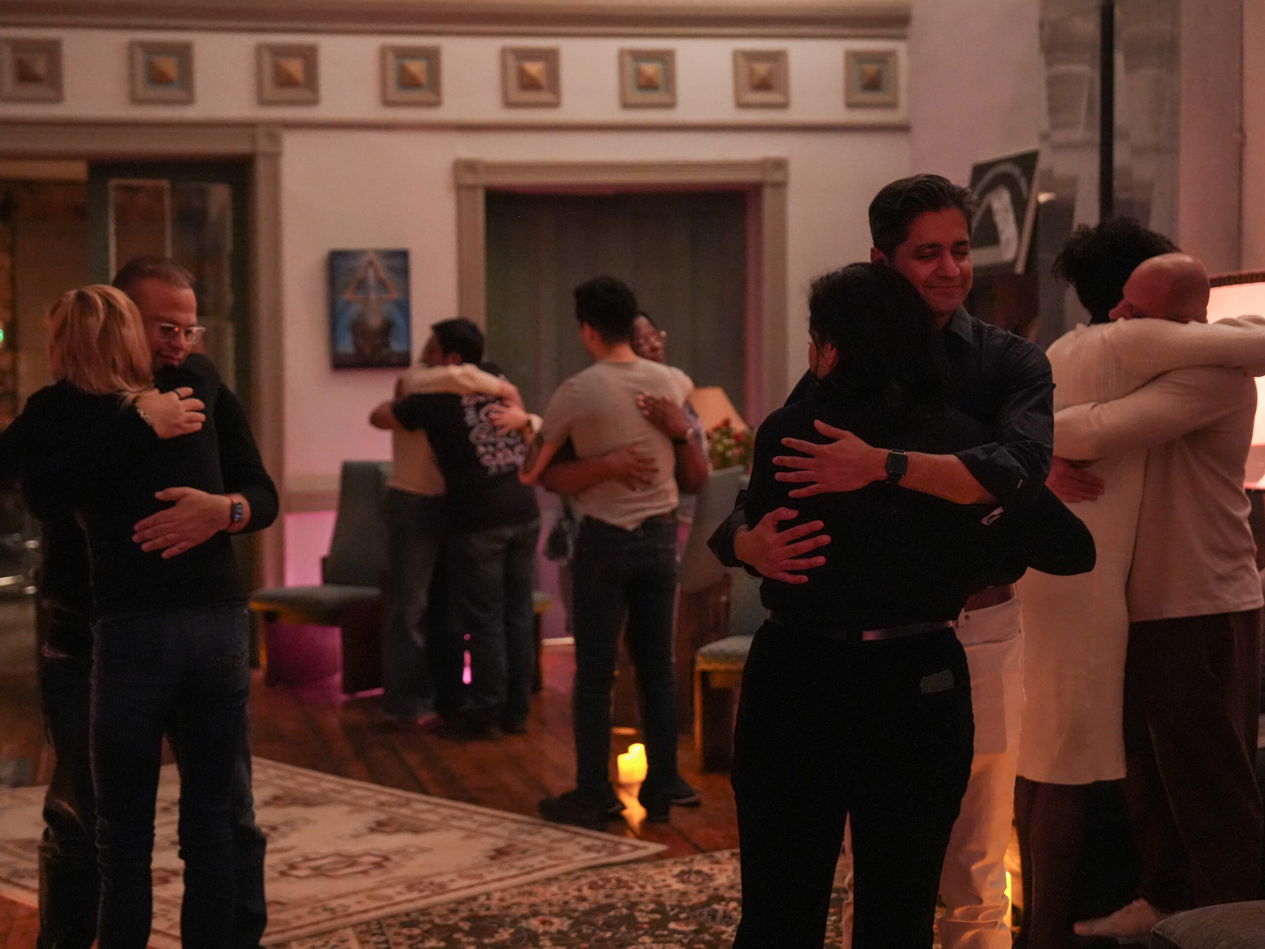 a wide room shot of a feels event in which participants are engaging in a somatic exercise of a long-held hug